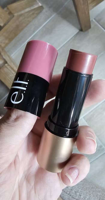 Person holding a two-tone e.l.f. cream blush stick, showcasing the product's texture and packaging
