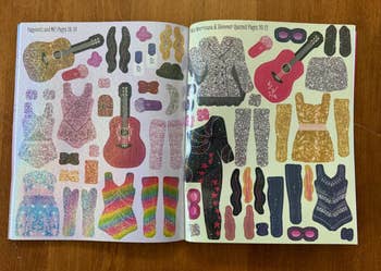 Open book with sparkly fashion stickers, including guitars, clothes, and accessories