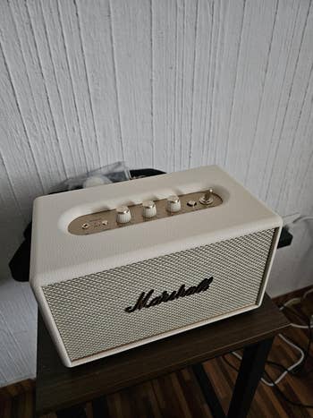 Speaker on a table, featuring four knobs and a brand logo