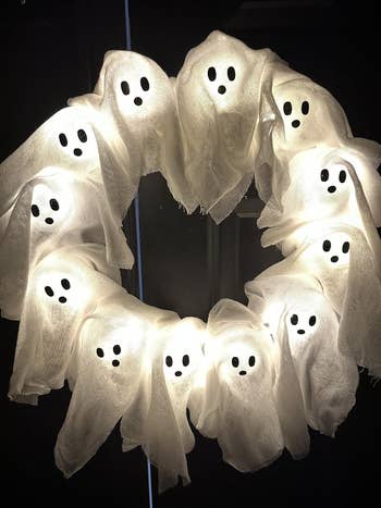 A wreath made of illuminated ghost decorations, ideal for Halloween-themed home décor