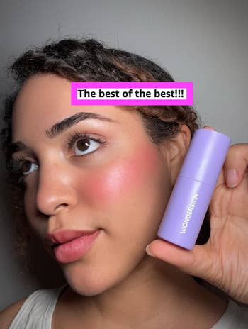 Person holding a purple WonderSkin product next to their cheek, smiling for a shopping article. Text reads: