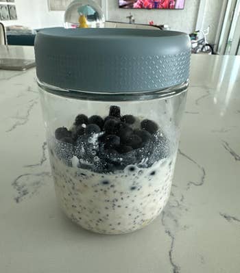 Jar of overnight oats with chia seeds and blueberries on a kitchen counter