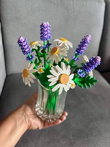 Artificial bouquet of daisies and lavender in a clear vase, held in a hand, showcasing a decorative floral arrangement