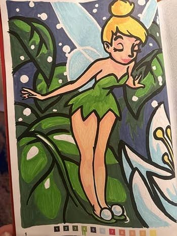 Illustrated fairy with wings wearing a leaf dress, standing among large leaves