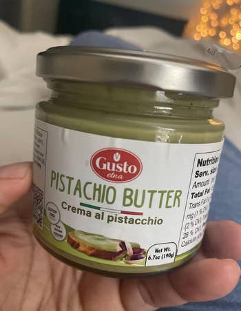 Jar of pistachio butter held in hand, labeled