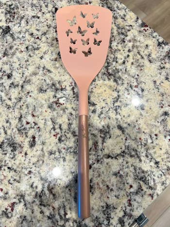 Spatula with butterfly-shaped cutouts on the blade, designed for decorative kitchen use, placed on a granite countertop