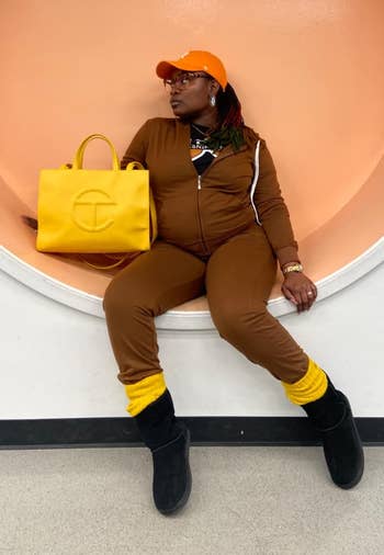 Person posing with a bright yellow tote bag, brown outfit,