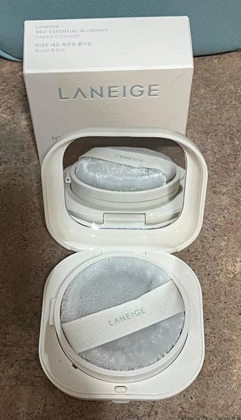 Laneige Essential Blurring Finish Powder with puff in open compact, packaging visible in the background on a table
