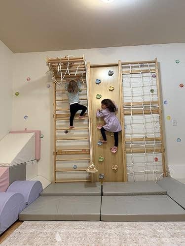 Two children climb an indoor play gym with a wooden climbing wall and net, highlighting home gym equipment for active play in a shopping context