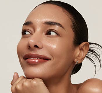 Smiling person with sleek hair and glowing skin, showcasing a dewy makeup look