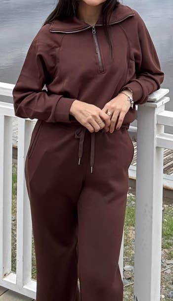 Person wearing a comfortable, casual top and pants with a zip and drawstring detail, standing by a railing outdoors