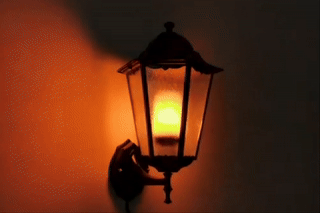 Wall-mounted lantern-style light fixture with LED that looks like a burning candle inside