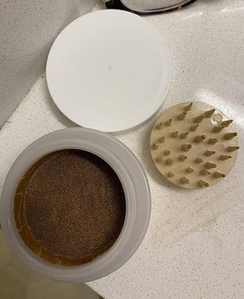 An open jar of powder makeup with a freckle stamp next to it