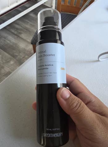 Hand holding a bottle of Meditherapy Retinal Skin Booster serum, promoting even skin tone and youthful-looking skin
