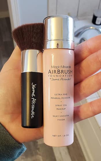 Hand holding a brush and a bottle of MagicMinerals AirBrush Foundation by Jerome Alexander. The foundation promises an ultra-fine, silky smooth finish