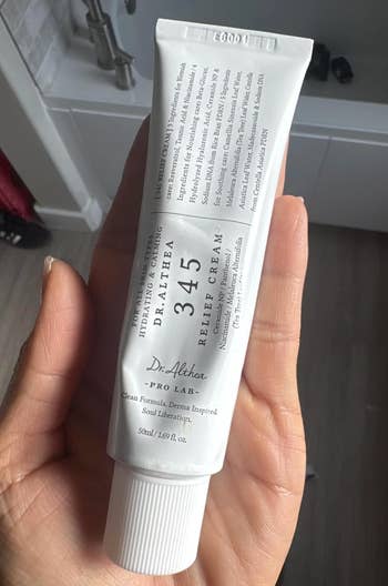 Person holding a tube of Dr. Althea 345 Relief Cream in their hand, highlighting a skincare product
