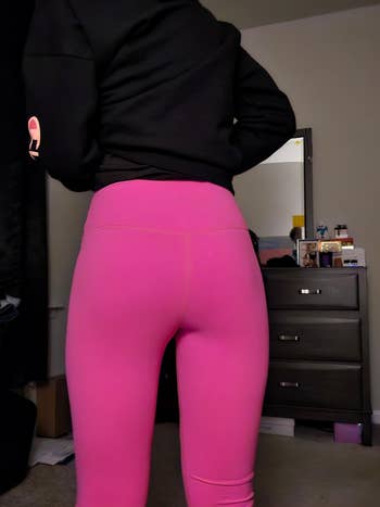 Person wearing bright leggings and a hoodie, standing in a room with a dresser in the background