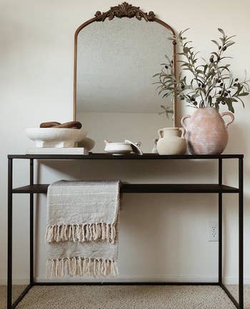 arched mirror with gilded detail on the top displayed on an entryway table