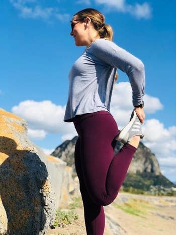 Reviewer stretching in the full-length leggings in purple.