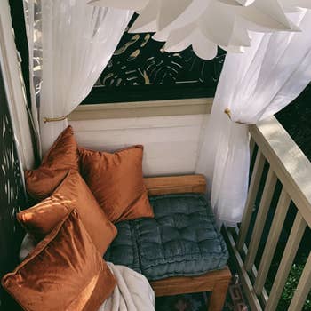 reviewer's covered deck with several pillows and the cushion on top of a wooden stool