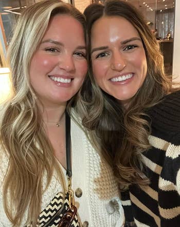 Two people smiling; one wearing a cream cardigan, the other in a black and white patterned sweater