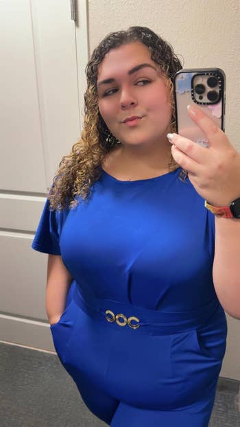 Person in blue outfit with a stylish gold-belt detail, taking a mirror selfie