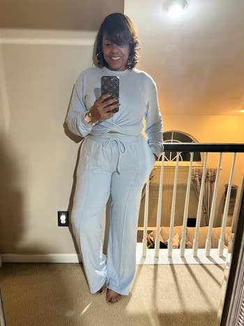 Person in cozy, long-sleeve lounge set with tied waist, taking a mirror selfie at home
