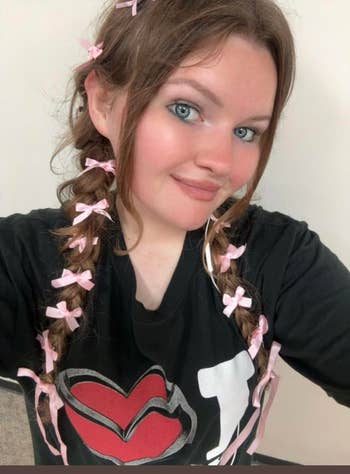 reviewer with braided hair tied with small ribbons, wearing a graphic t-shirt with a large heart design, smiling at the camera