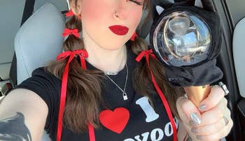 reviewer with red bows holds a lightstick, wearing a shirt with 