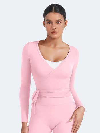 A person wears a stylish, wrap-top athletic outfit with long sleeves, posing