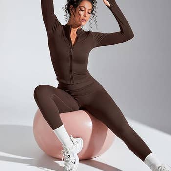 Person posing in a fitted, ribbed activewear set on an exercise ball, wearing white sneakers and socks