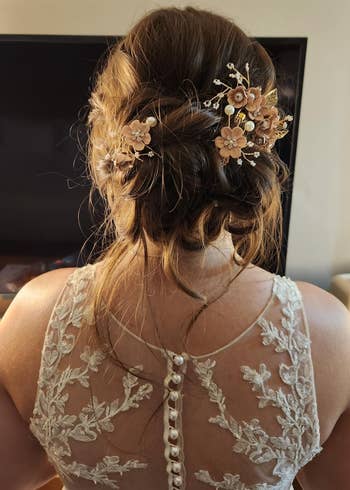A reviewer's Elegant bridal hairstyle with floral hairpins, featuring a lace dress with floral embroidery on the back, suitable for a wedding-themed article