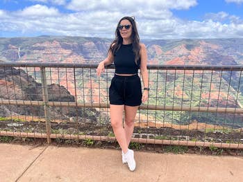 reviewer in casual black outfit with sunglasses stands on a scenic overlook