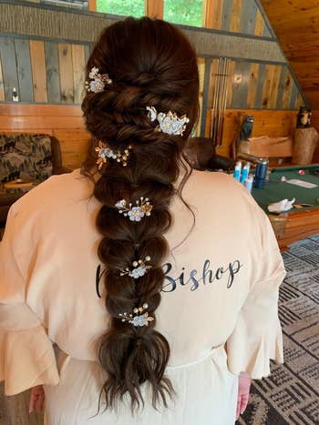 A reviewer's Braided hair adorned with floral hairpins; person wearing a robe